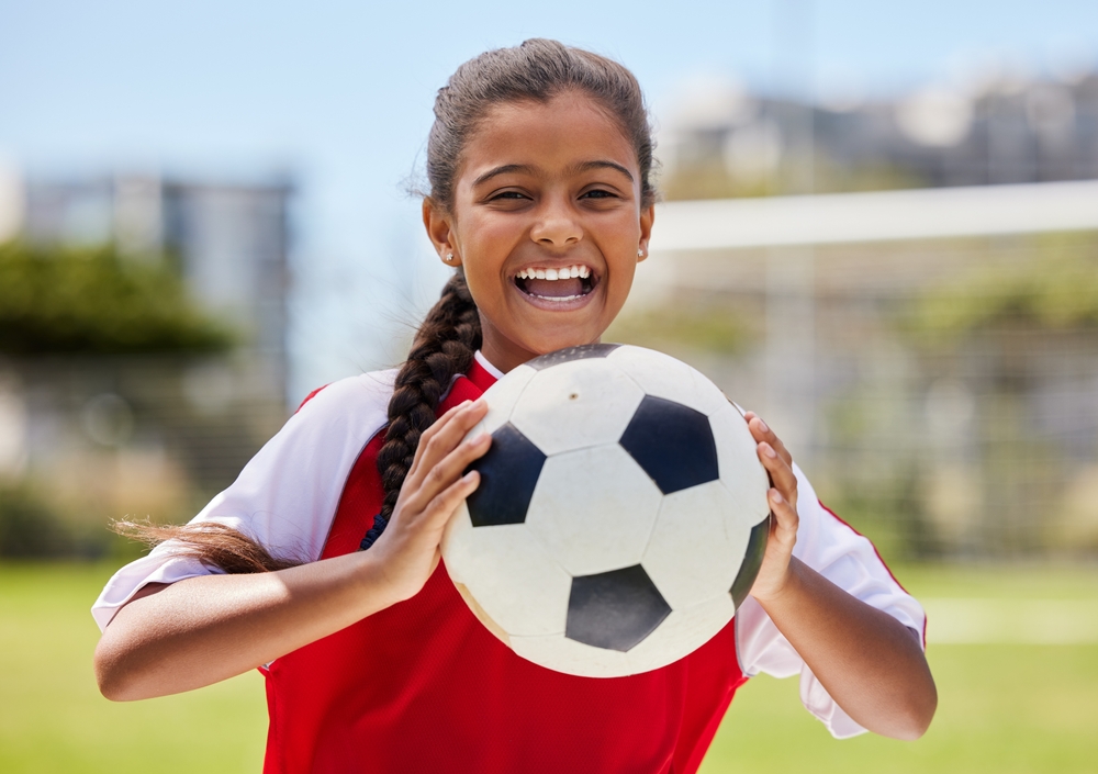 young girl holding a soccer ball.